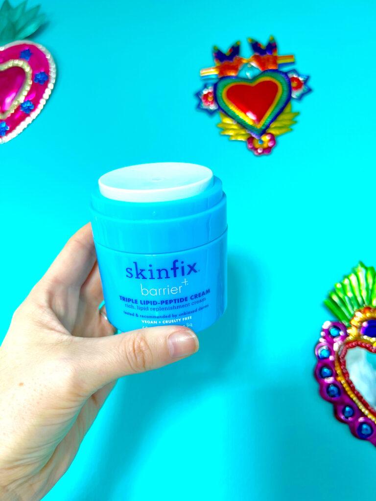 Hand holding a small tun of Skinfix Triple Lipid Peptide Cream