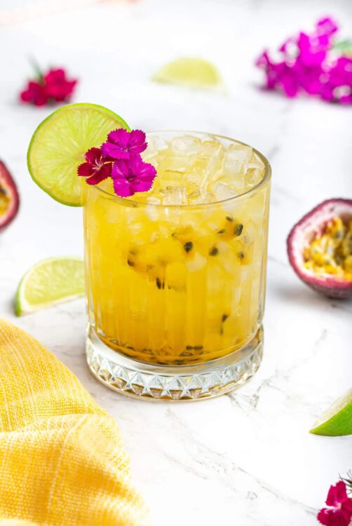 A passionfruit mocktail garnished with a magenta flower and lime slice, which is one of the best non-alcoholic drinks for summer