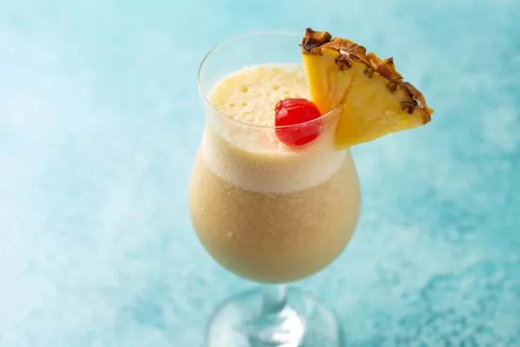 A virgin piña colada garnished with a slice of pineapple and maraschino cherry