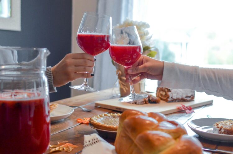 Two glasses of a pink, cider-like beverage positioned to cheers