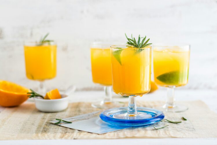 A shot of four glasses of non-alcoholic mimosas, which are great Thanksgiving mocktails