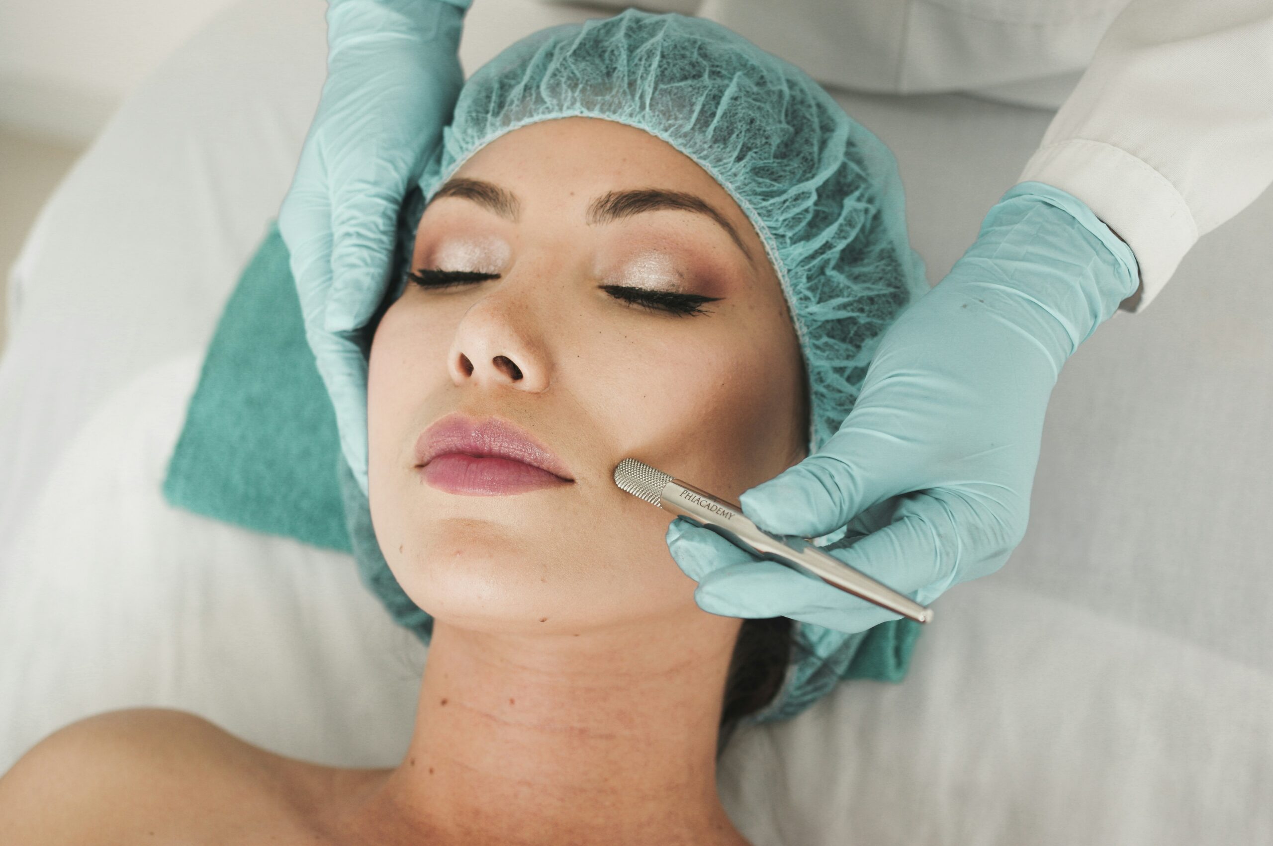 Person wearing a teal hair net getting a microdermabrasion treatment
