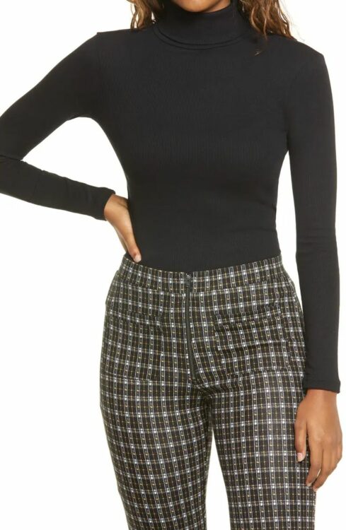 A model wearing a black turtleneck with plaid pants