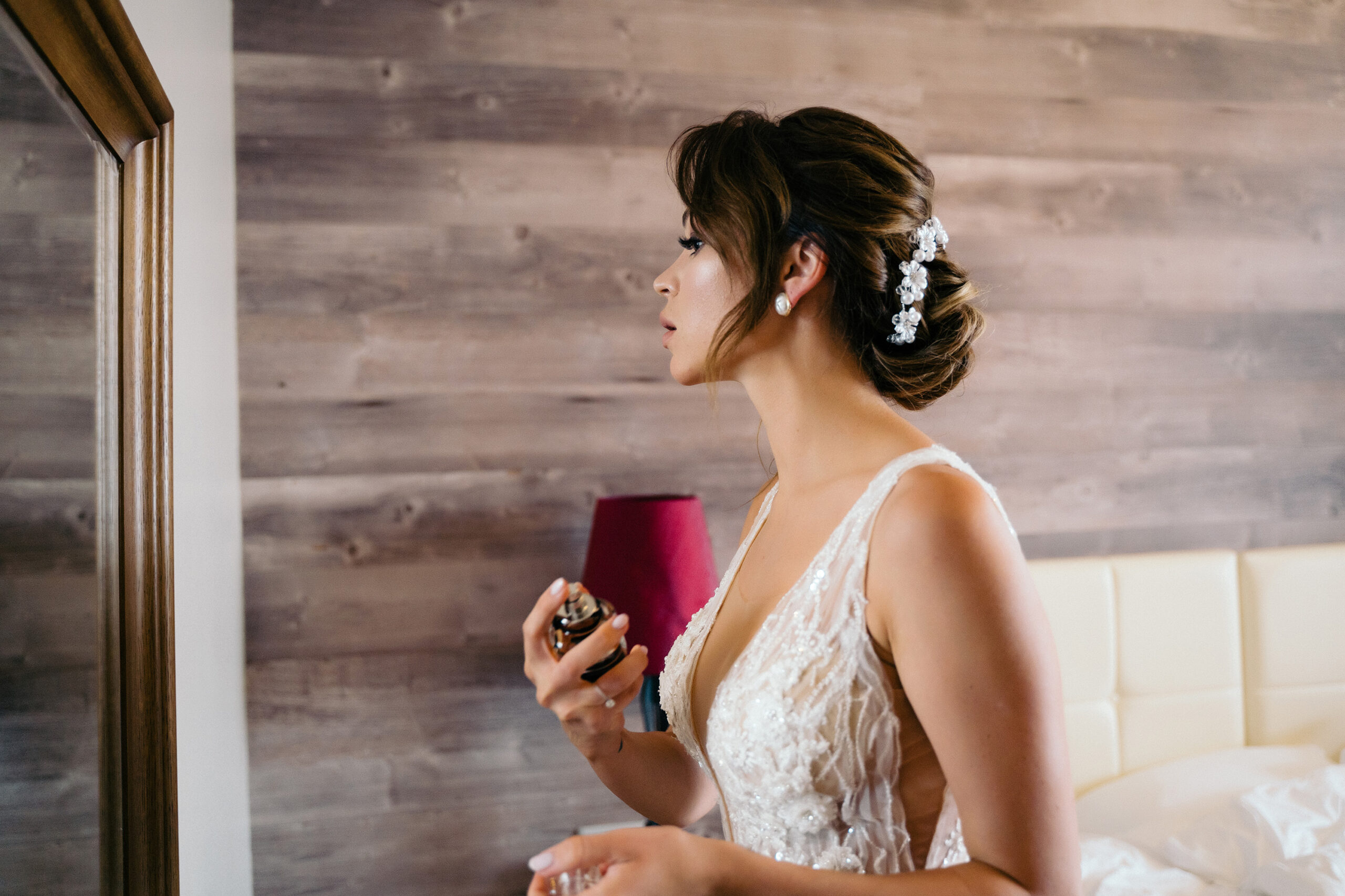 Person in the mirror sprays fragrance while wearing a wedding dress