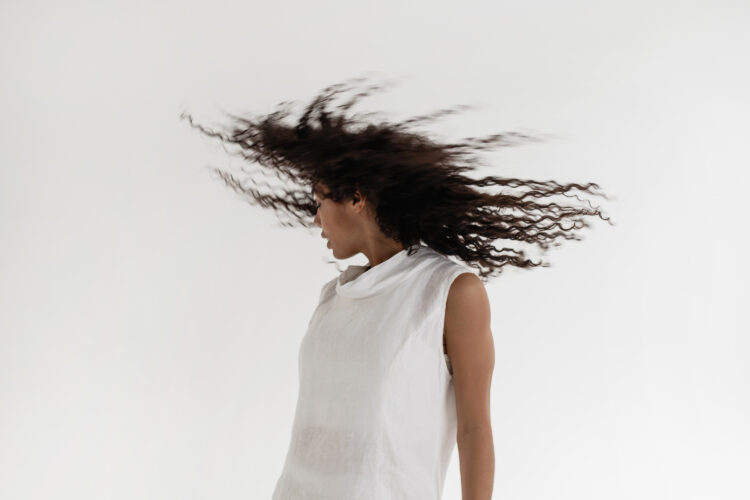 Person in a white shirt on a white background swings their hair around