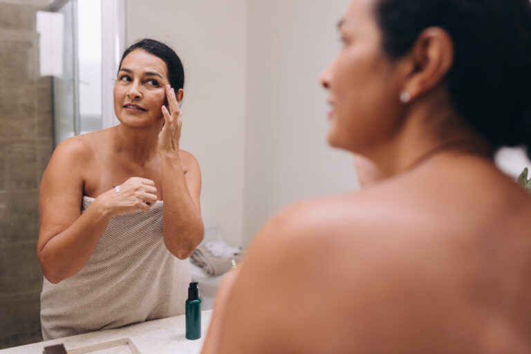 Person wearing a towel preps their skin for makeup application