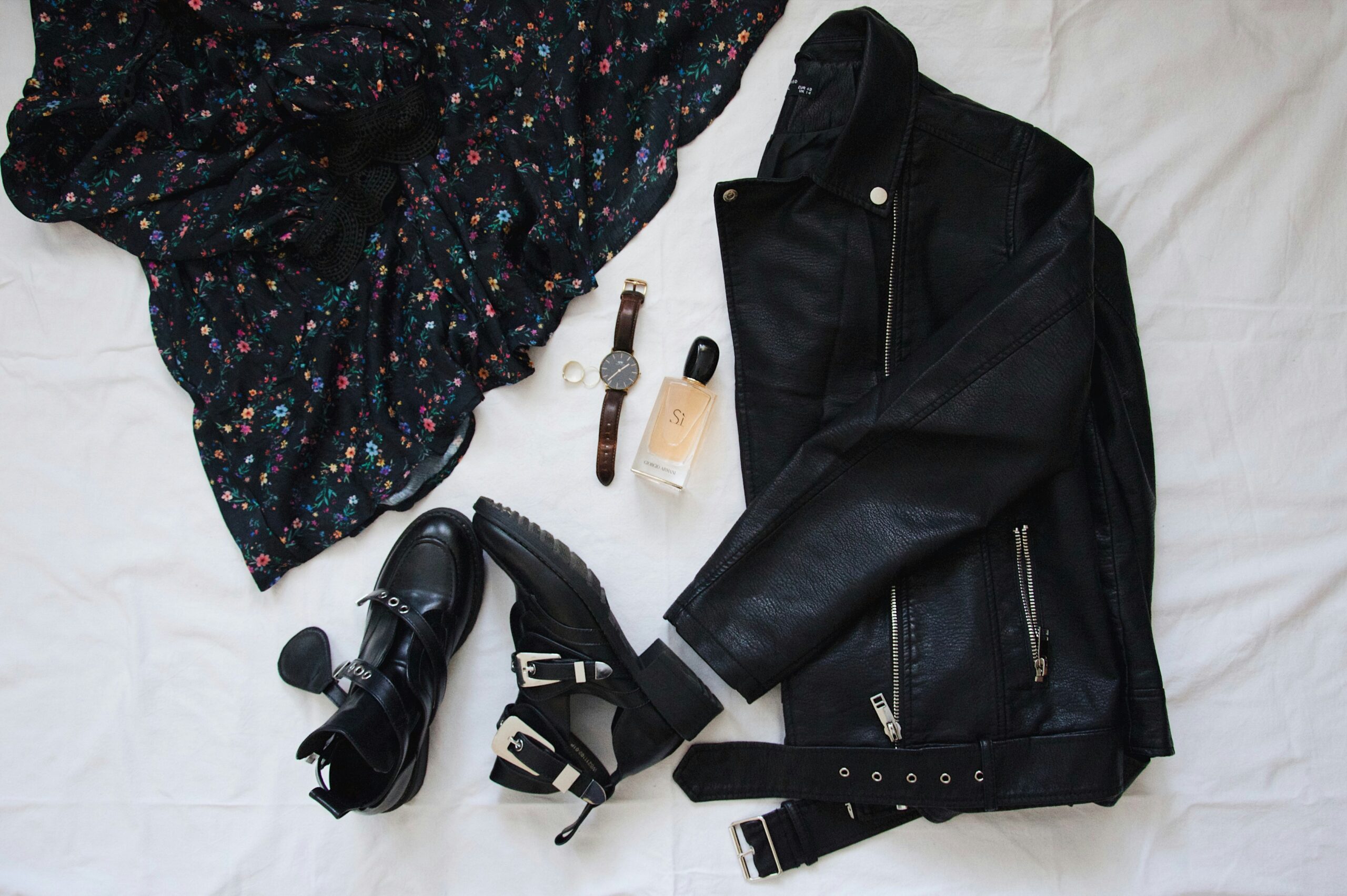 A layout of a floral dress outfit with a leather jacket and boots