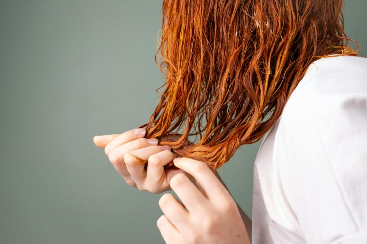 Person scrunching their red, wet hair with both hands