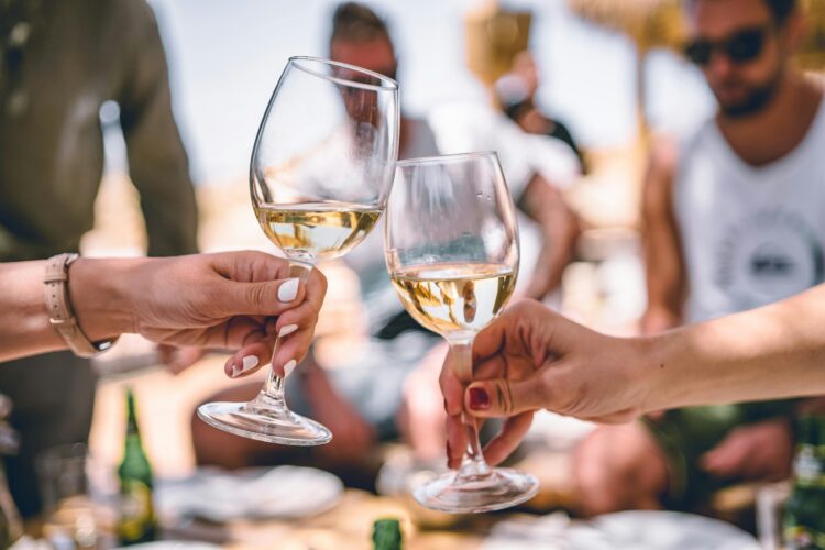 A close-up of two people holding their wine glasses up to cheers