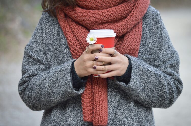 Person wearing a gray cardigan and a red scarf, showing one of many ways to wear a scarf