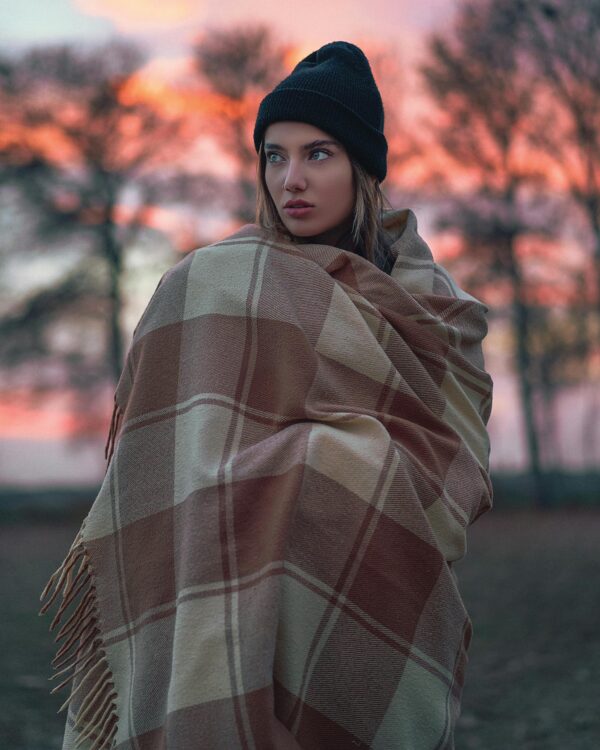 Person wearing a black beanie and a plaid blanket scarf, which is one of many ways to wear scarves