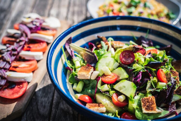 A bowl of salad and a plate of caprese next to it