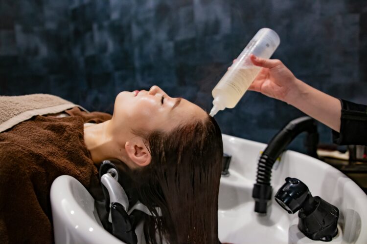 Person getting a solution poured on their head to make their hair less greasy