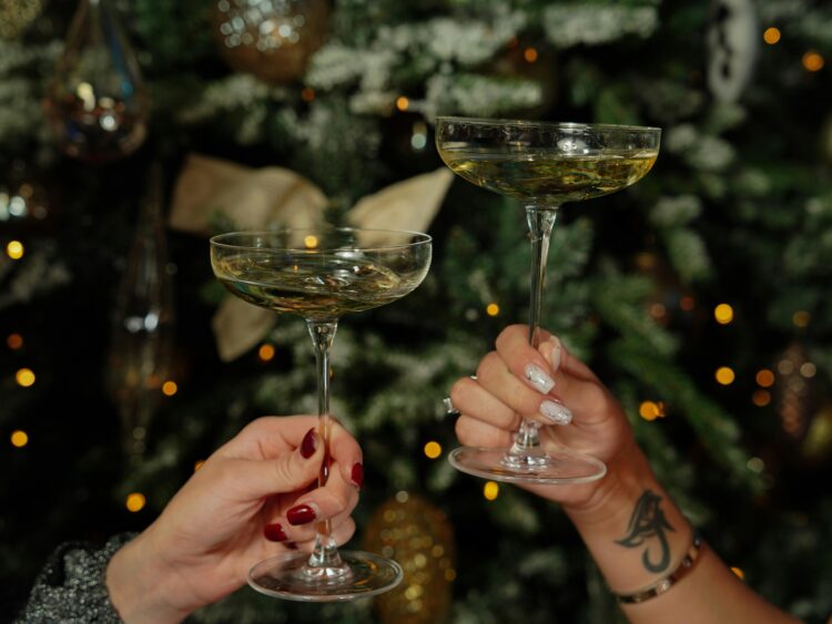 Two hands holding thin-stemmed glasses holding Christmas mocktails